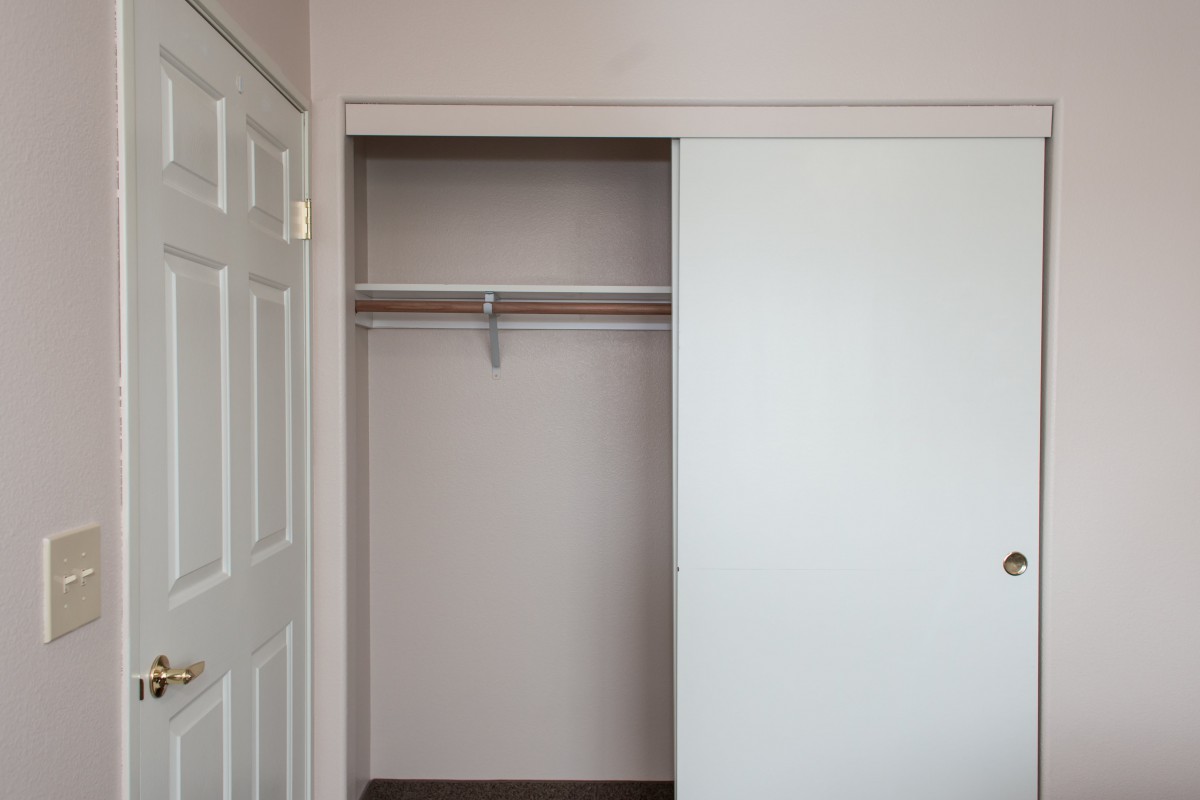 An empty closet with a sliding door and a single shelf.