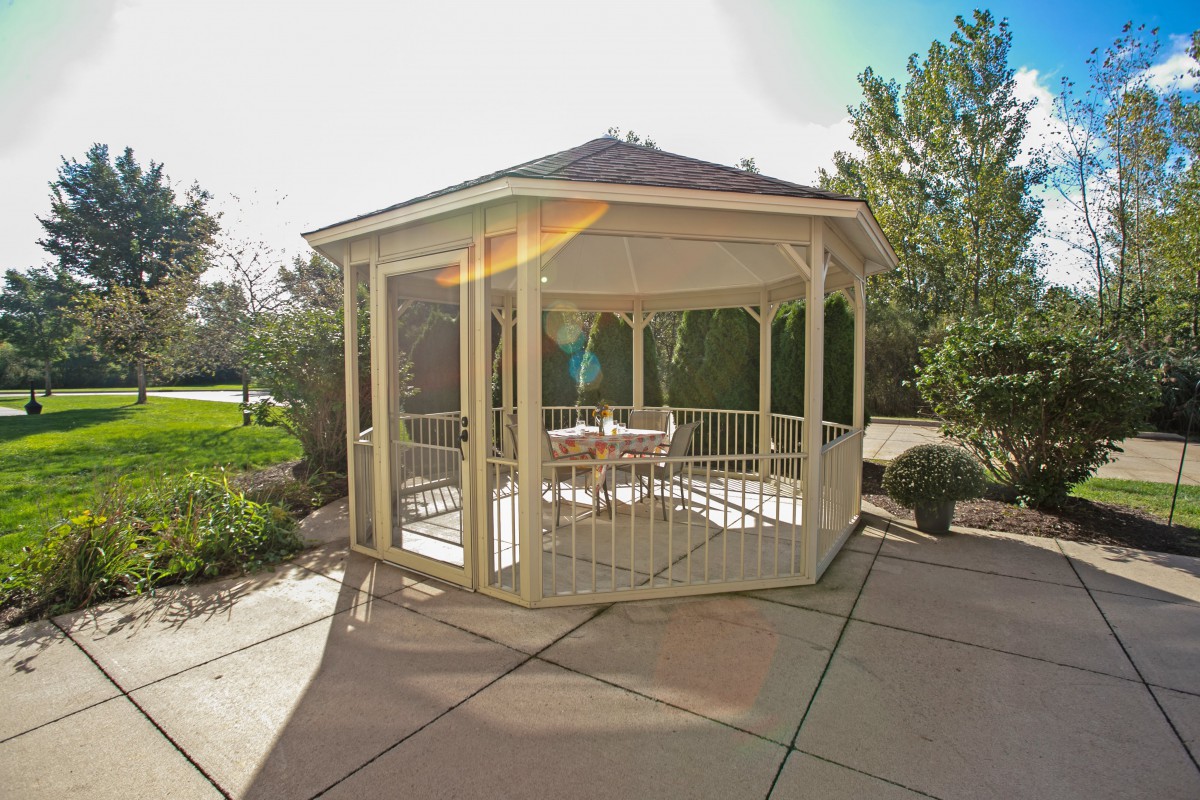 A charming gazebo situated in a sunny garden patio setting.