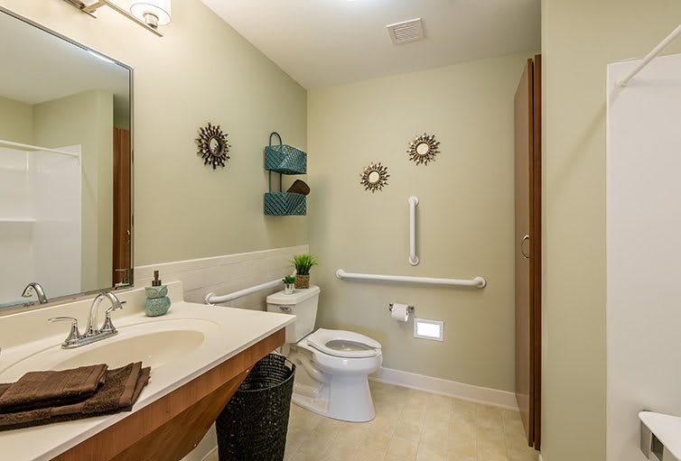A clean and organized bathroom with wall decor, a grab bar, and a compact layout.
