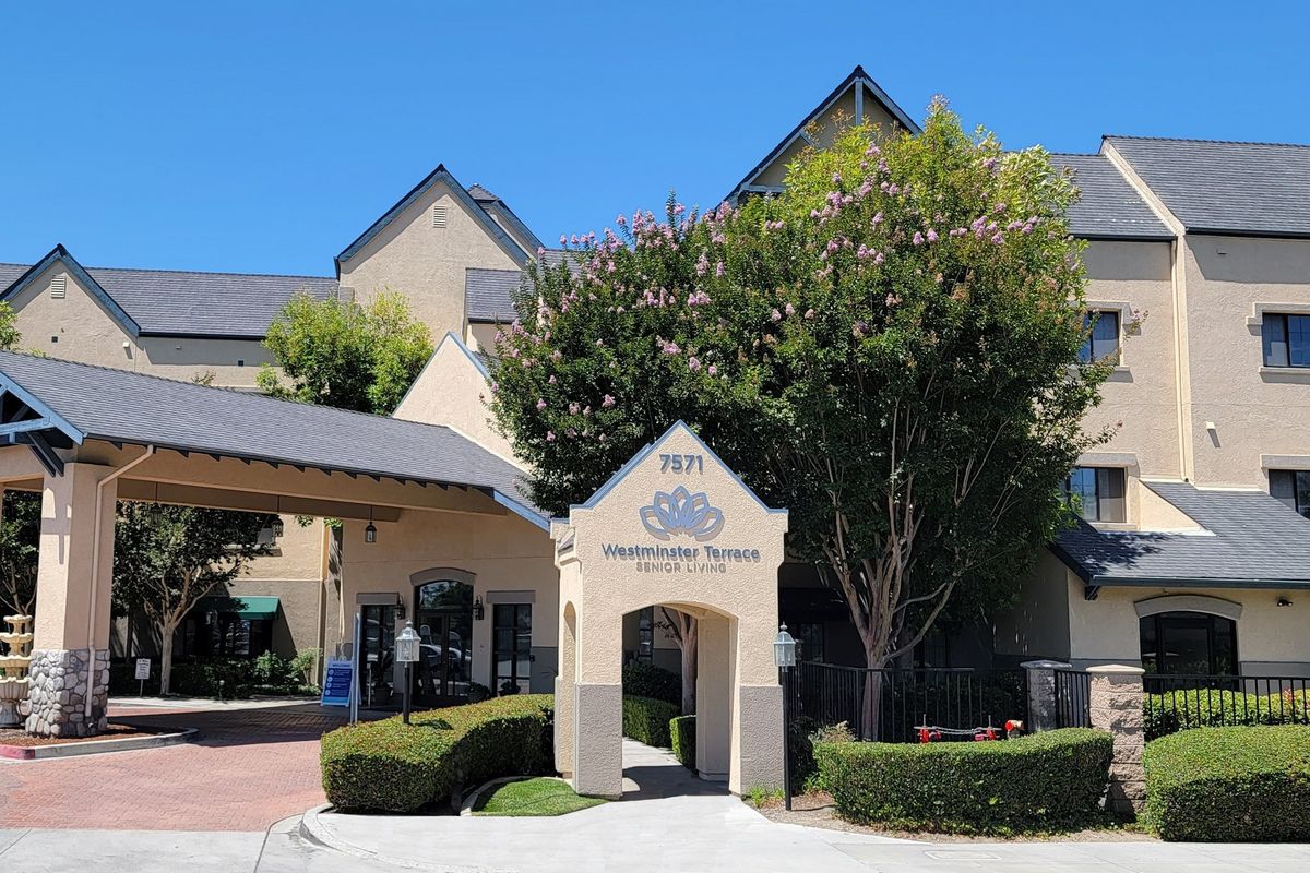 The exterior view of a hotel entrance surrounded by trees.