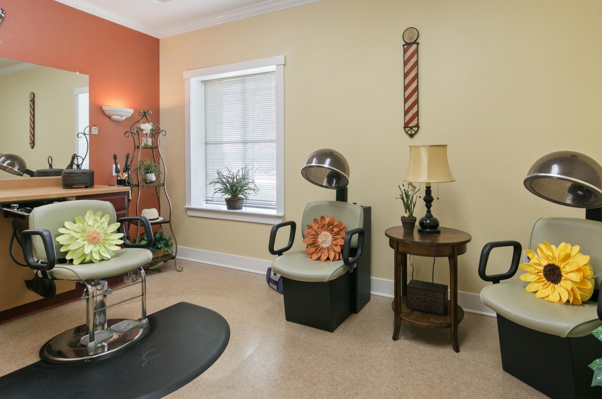 A cozy salon interior featuring chairs, a hair dryer, and decorative elements.