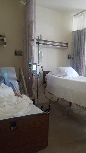 A hospital room featuring two beds with patients and medical equipment.