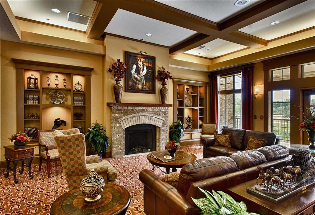 A traditionally decorated living room with a fireplace, coffered ceiling, and warm-toned furniture.