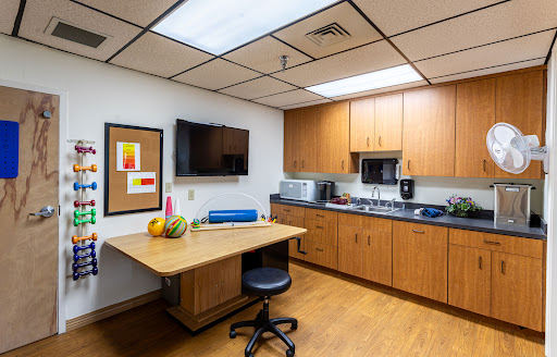 A cozy breakroom featuring a kitchenette with modern appliances, a desk, and inviting decor.