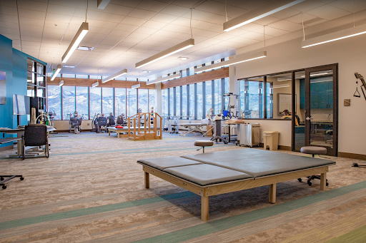 A spacious and well-lit therapy room designed for rehabilitation with modern equipment and large windows providing natural light.