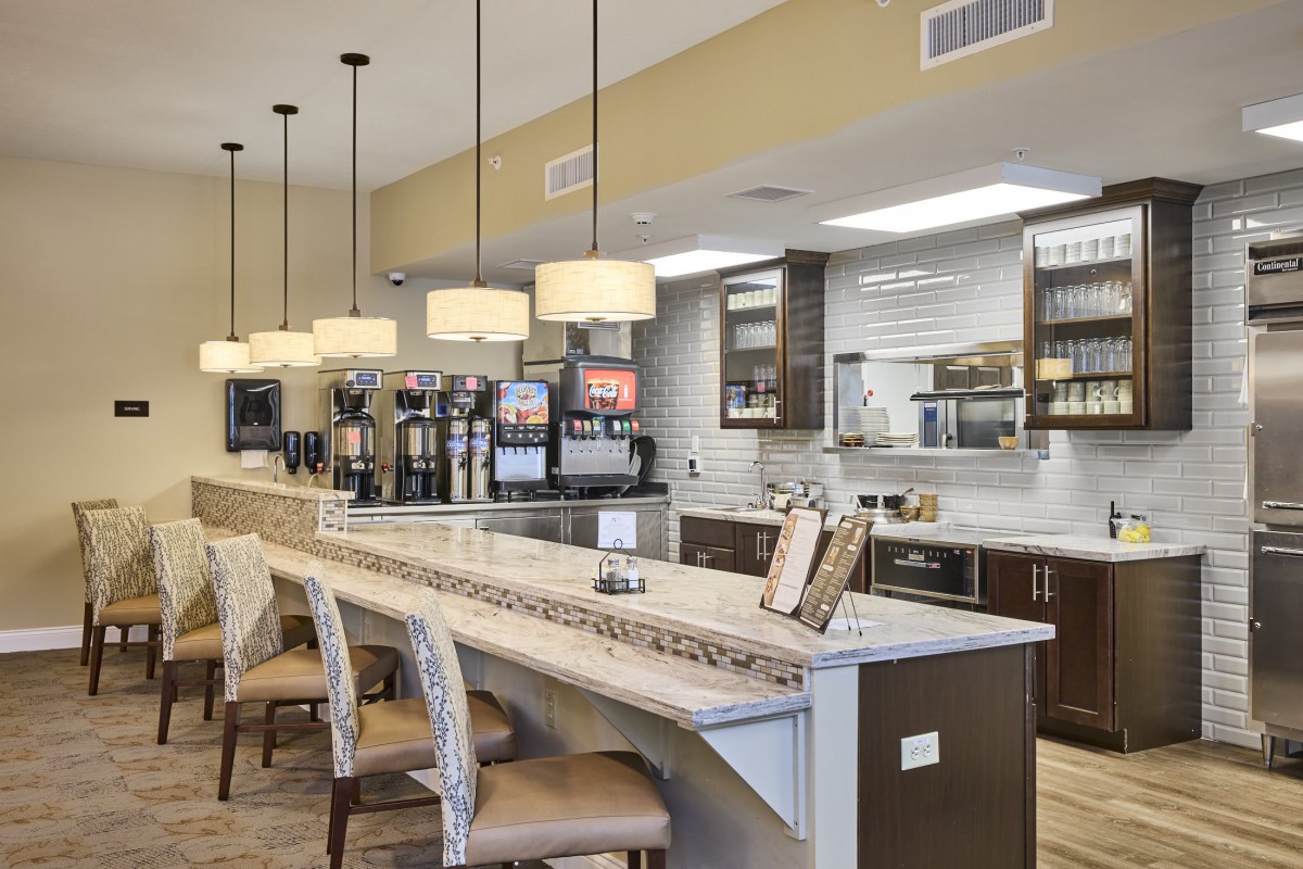 A modern kitchen interior featuring a cafe-style counter with seating and pendant lights.