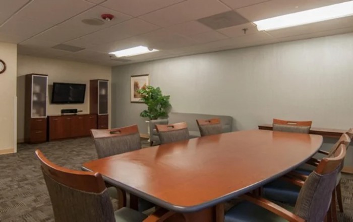 A well-lit conference room with a large meeting table and several chairs.