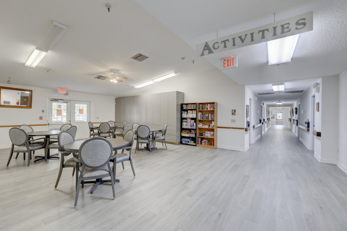 A community activities room with tables, chairs, and a bookshelf.