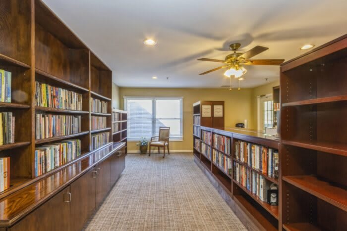 A cozy reading area with bookshelves lining the walls and a chair by the window.
