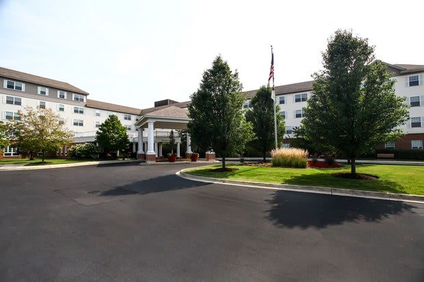 A well-maintained building with a circular driveway and landscaped gardens.