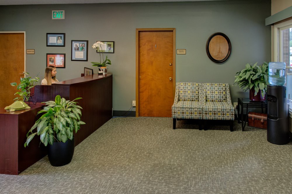 A welcoming office reception area with a desk, seating, and decorative plants.