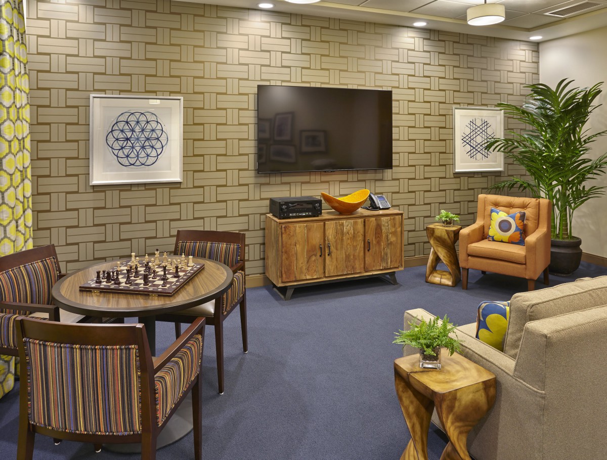 A cozy living room with a chessboard setup, featuring modern decor and wooden furnishings.
