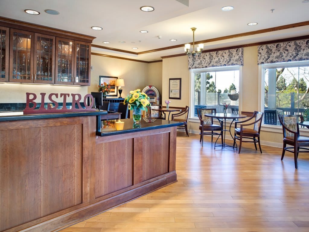 A cozy caf interior with a wooden counter and seating area, featuring ample natural light.