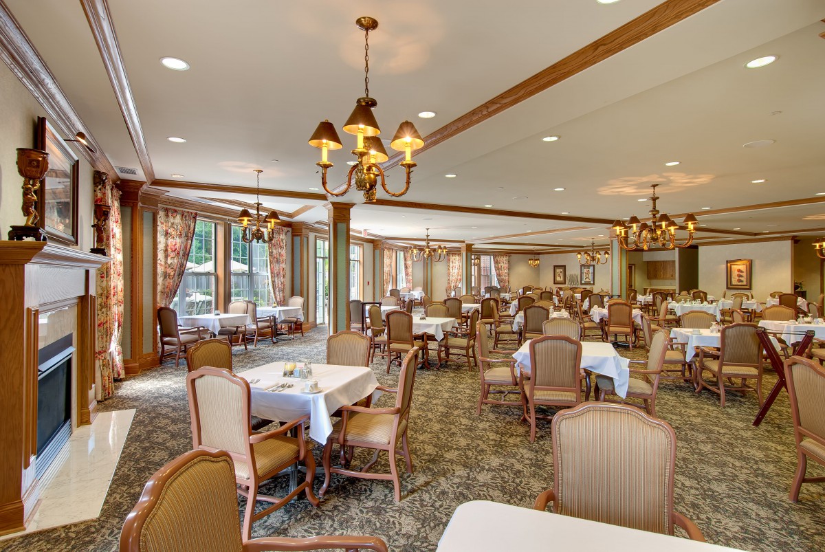 Elegant dining room with neatly arranged tables and chairs, adorned with chandeliers.