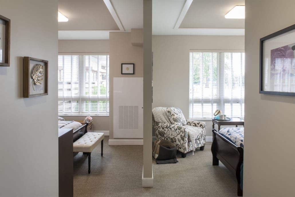 A bedroom interior showcasing a divided space with natural light streaming through large windows.