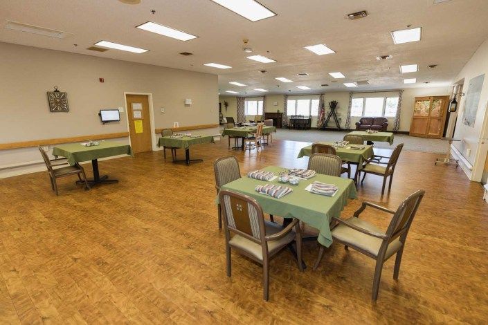 A spacious and well-lit community dining room with several tables and chairs, ready for use.