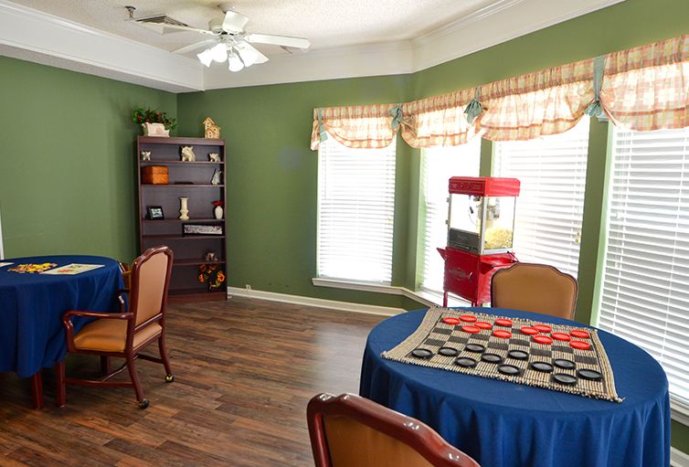 A cozy game room featuring a checkers table, chairs, and a popcorn machine by the window.