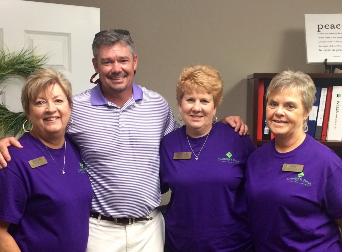A group of four people smiling together indoors.