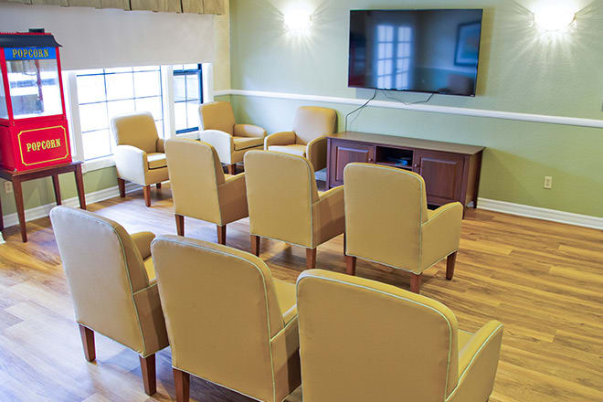 A cozy seating area with multiple chairs facing a large television in a well-lit room.