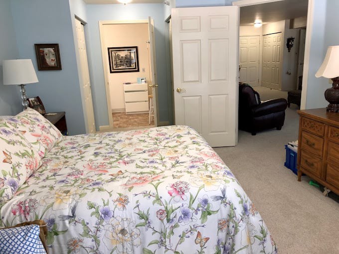 A cozy bedroom with a floral bedspread, blue walls, and an open closet.