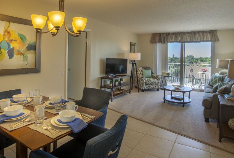A modern living and dining area with stylish furnishings, a television, and access to a balcony.