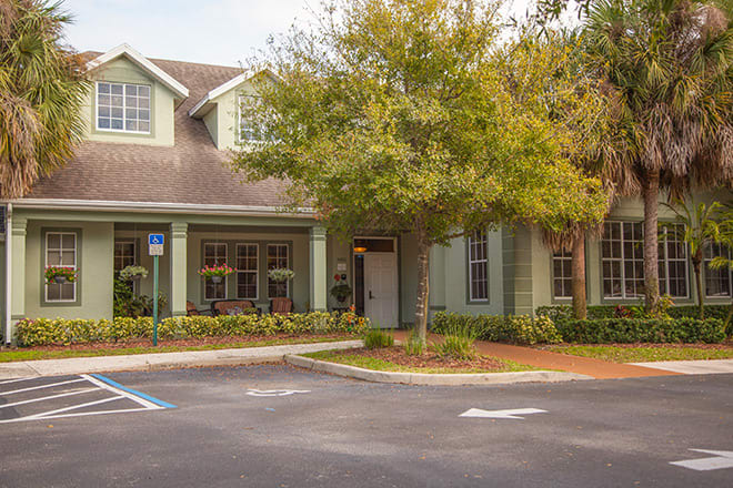 A residential building with a parking lot and landscaped surroundings.