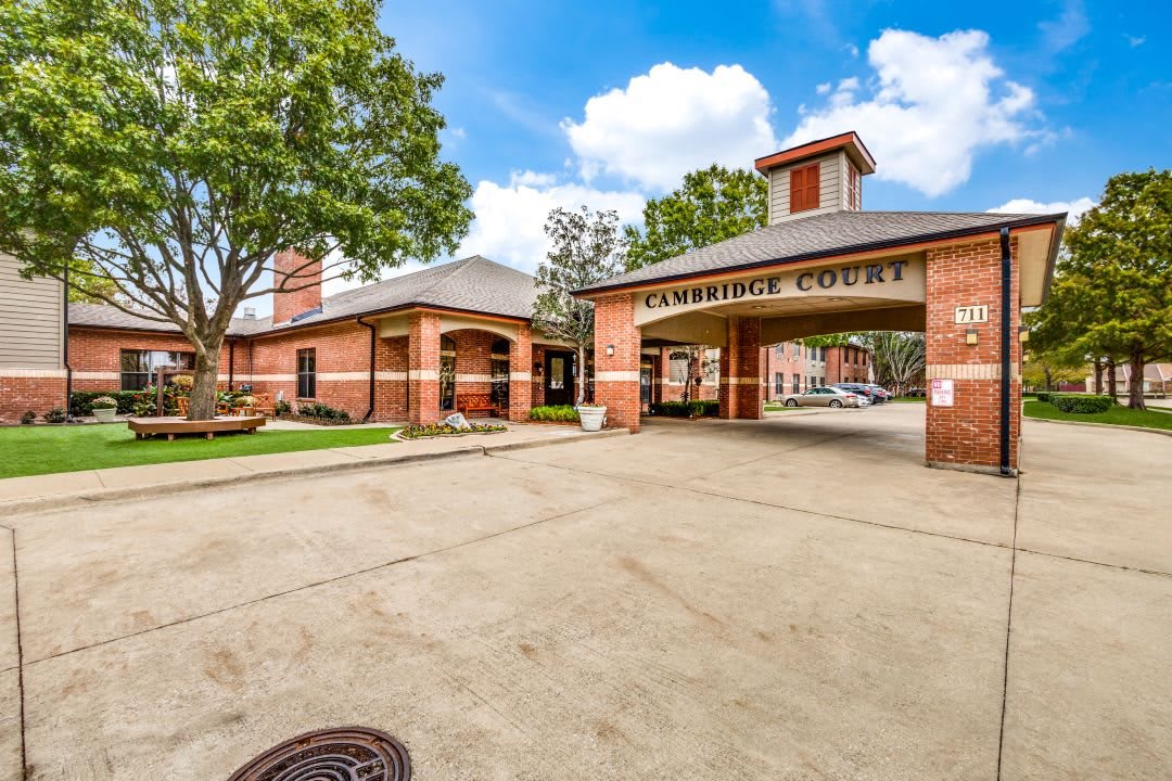 Entrance of a residential complex with a brick facade and driveway.