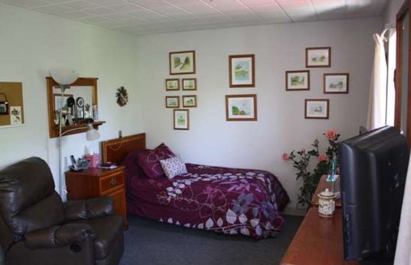 A cozy bedroom with a single bed, adorned with floral-themed decor and wall art.