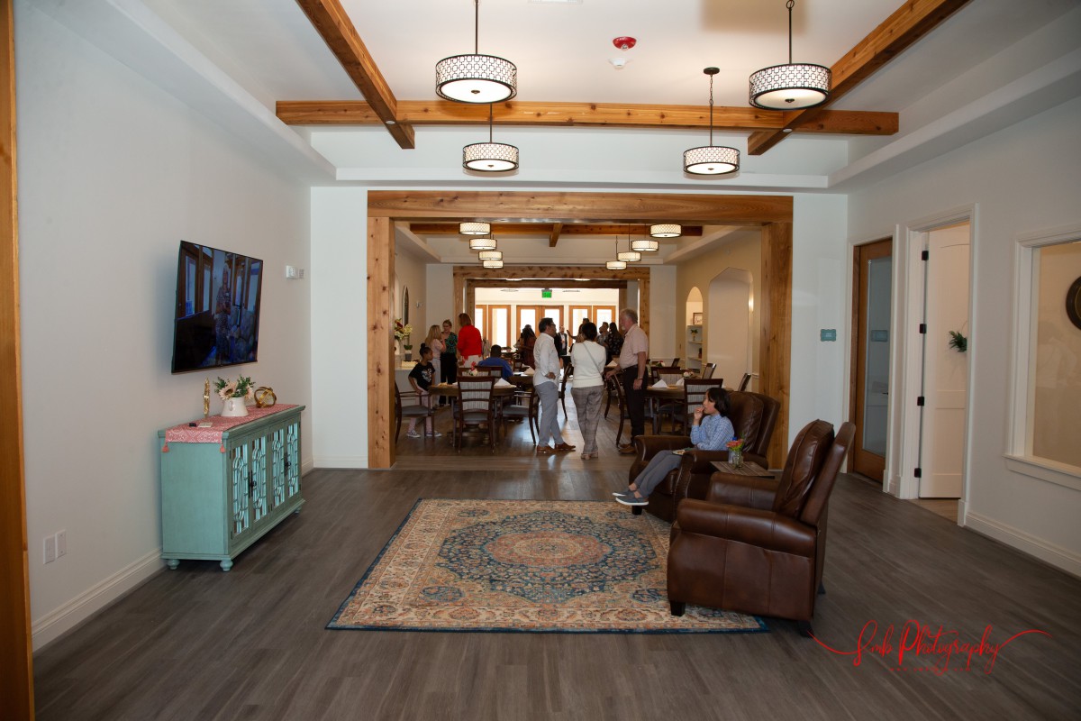 A cozy living room area with comfortable seating and people socializing in the background.