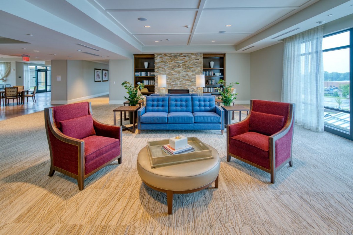 A modern living room with a blue sofa, two red armchairs, and a round coffee table.