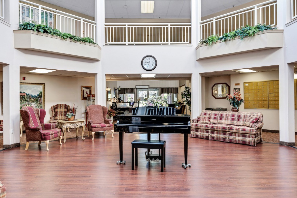 A spacious living room with a grand piano and comfortable seating.