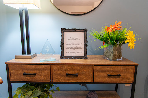 A stylish living room setup featuring a decorative frame on a wooden table, accompanied by plants and a lamp.