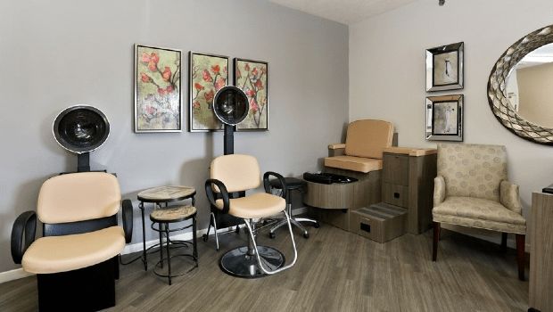 A modern salon interior with stylish chairs, a hairdryer, and artwork on the walls.