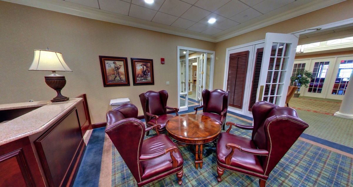 A cozy lobby seating area with armchairs and a round wooden table.