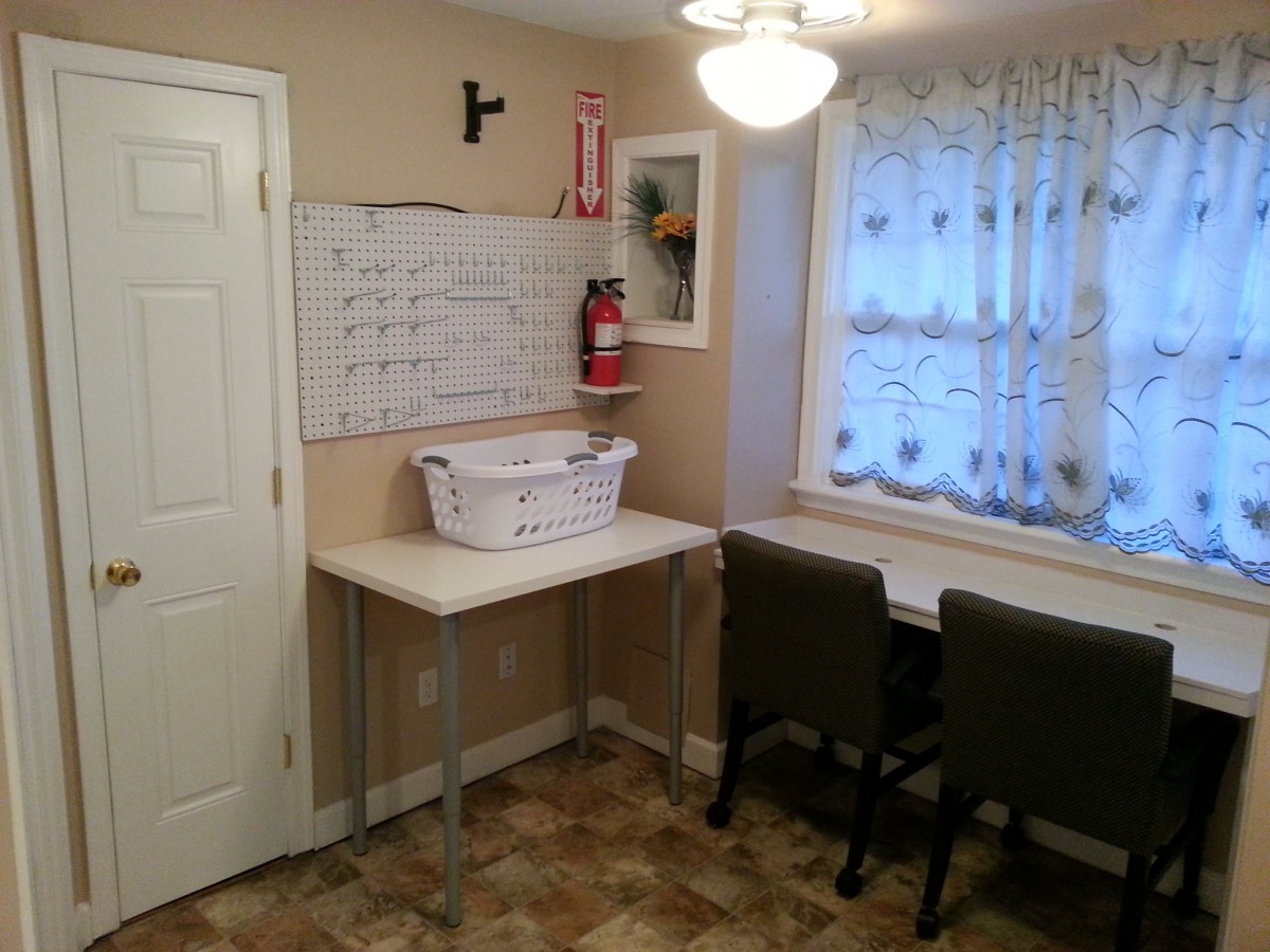 A cozy laundry room with a table, chairs, and a whiteboard.