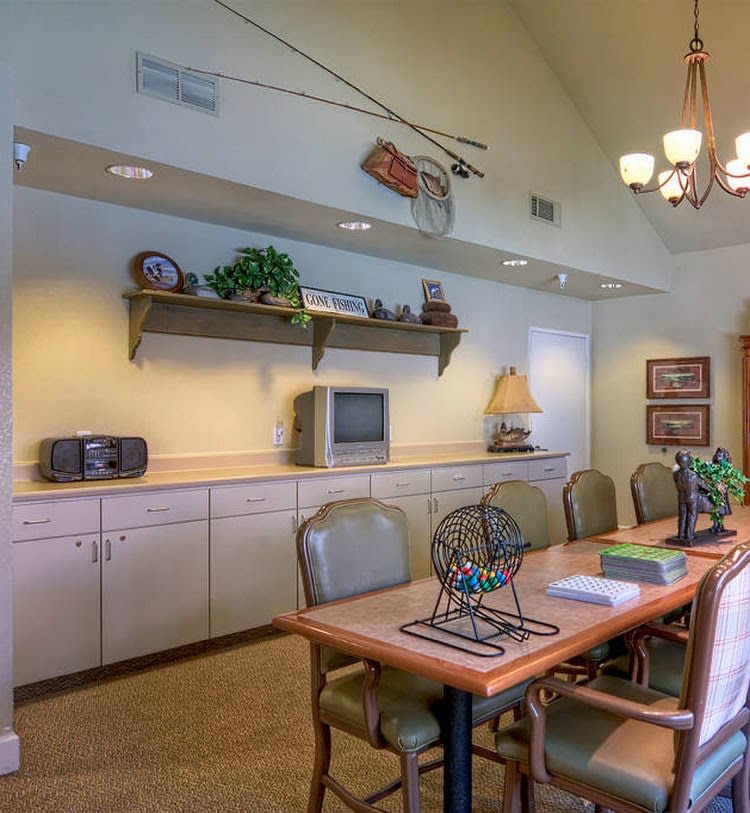 A well-lit conference room featuring a long table with chairs, decorated shelves, and a small television.