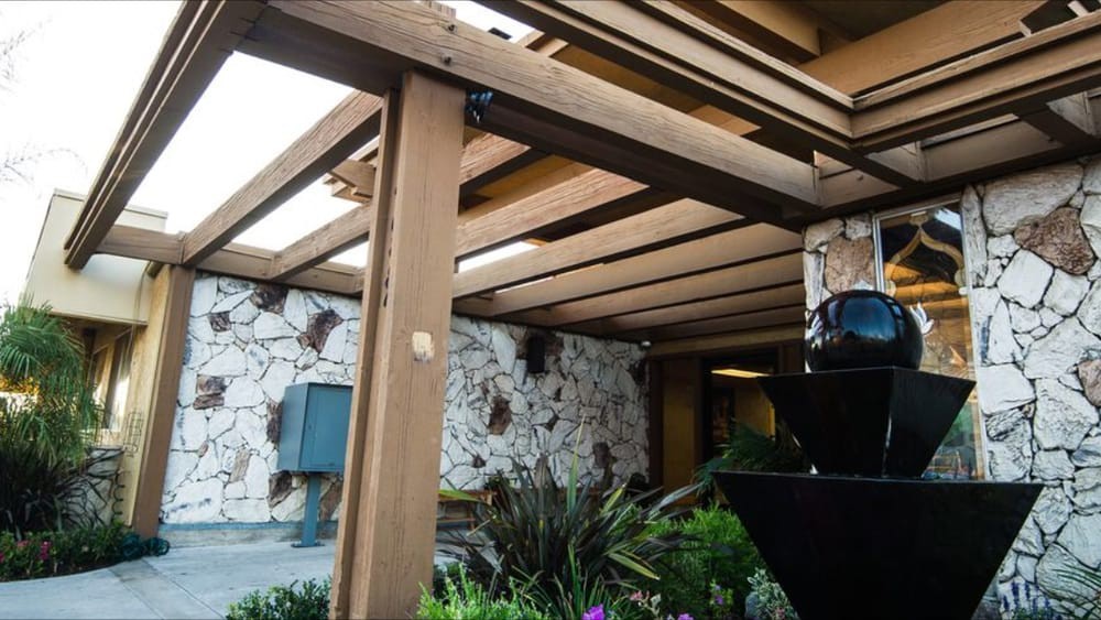 A pergola with wooden beams and lush greenery in a garden setting.