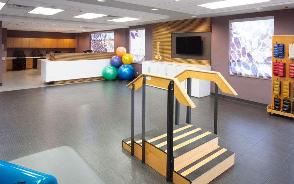 A well-equipped physical therapy room with exercise balls and a rehabilitation staircase.