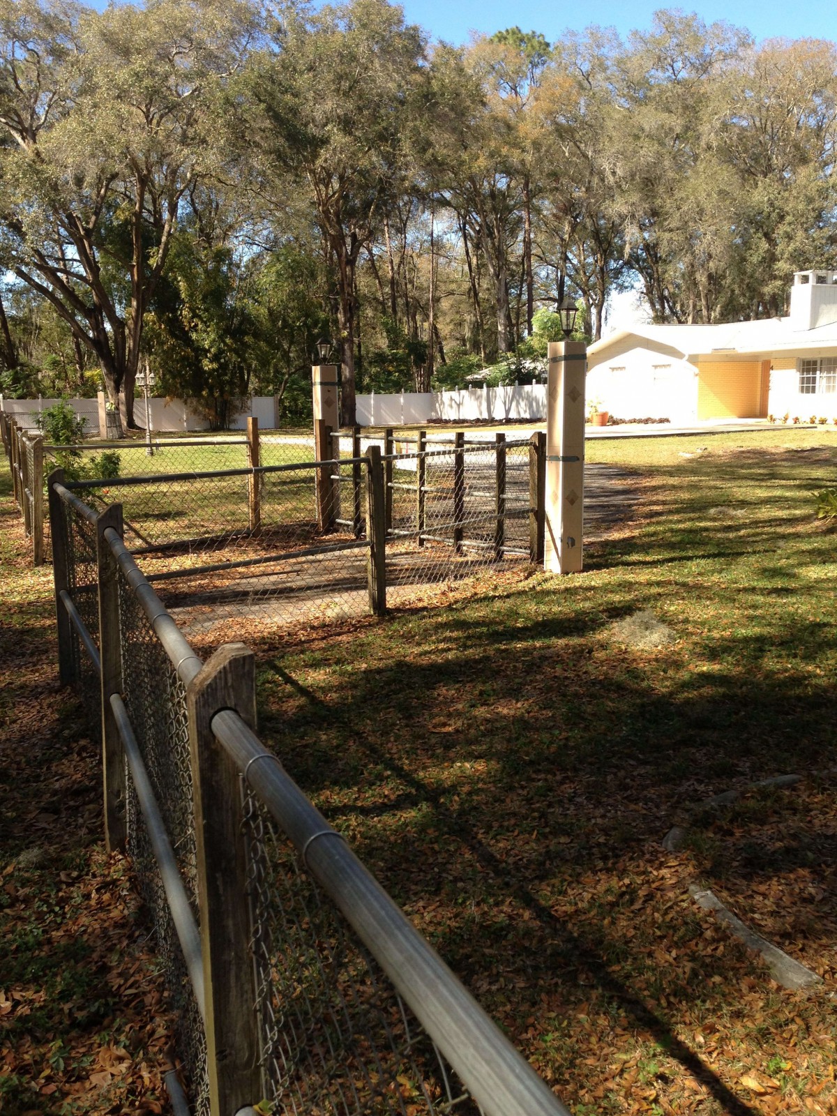 A fenced pathway leading to a gate with a house visible in the background.