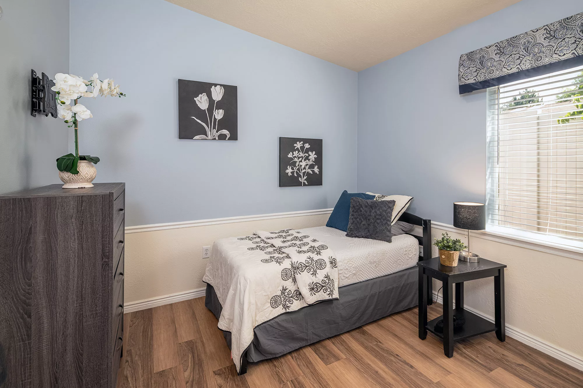 A cozy bedroom with blue walls, a single bed, and modern decor.