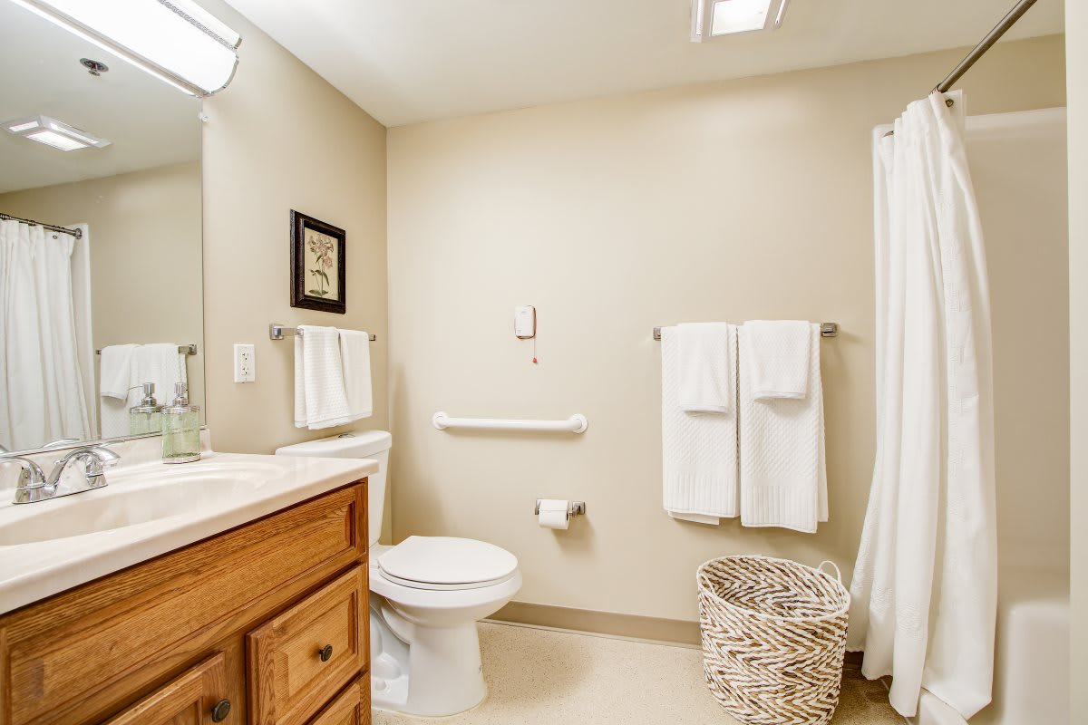 A clean and minimalist bathroom with beige walls, a vanity sink, and neatly hung towels.