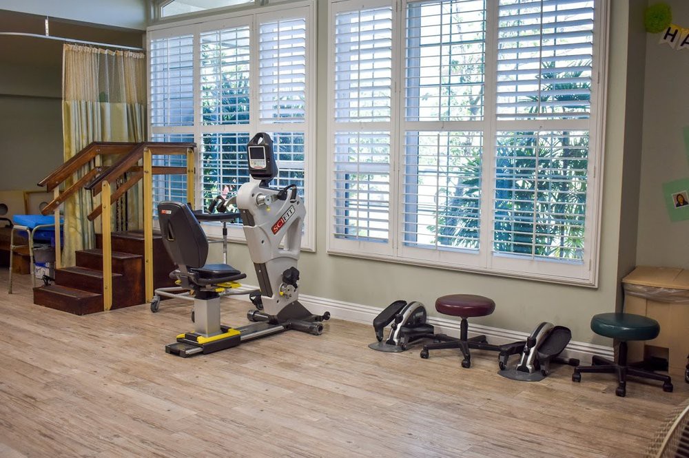 A well-lit home gym with various exercise equipment and weights.