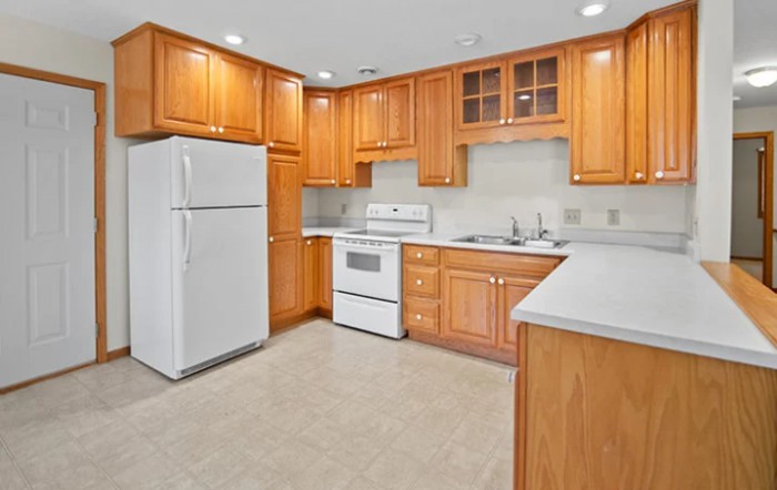 A spacious kitchen with wooden cabinets and white appliances.
