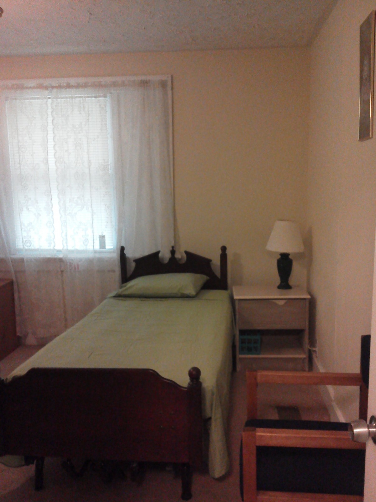 A simple bedroom with a single bed and side table.