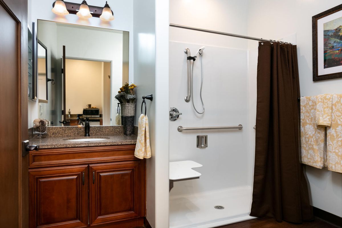 A modern bathroom featuring a shower with accessibility features and a wooden vanity unit with a sink.