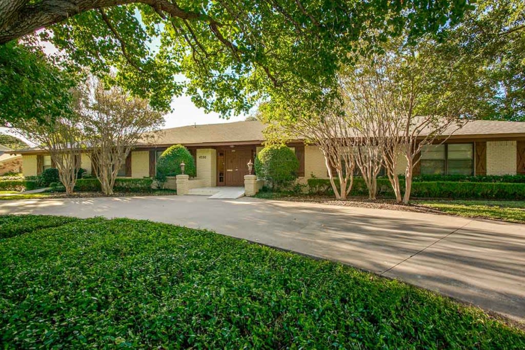 A suburban house with a spacious driveway and lush landscaping.