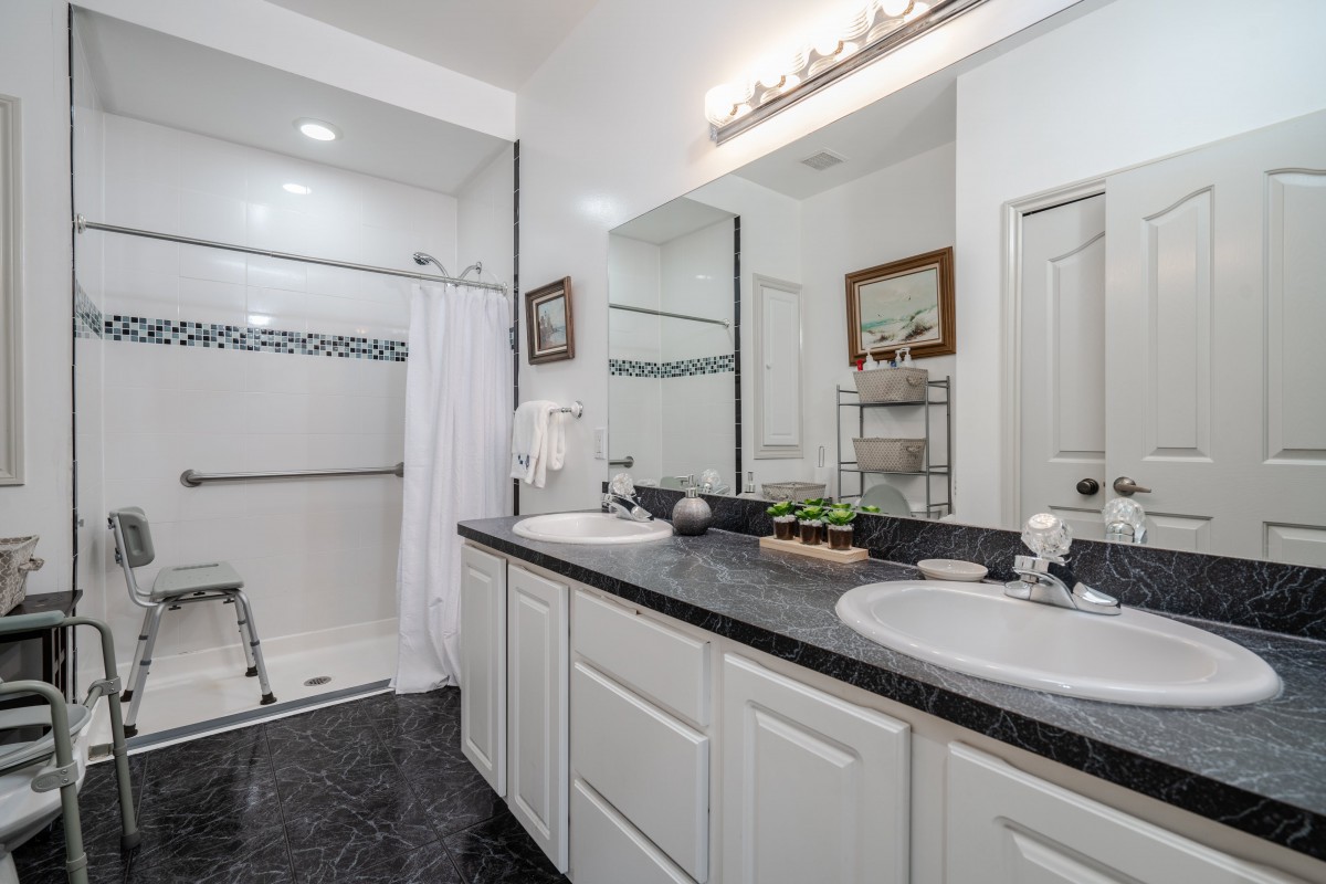A modern bathroom with a double vanity and spacious shower area.