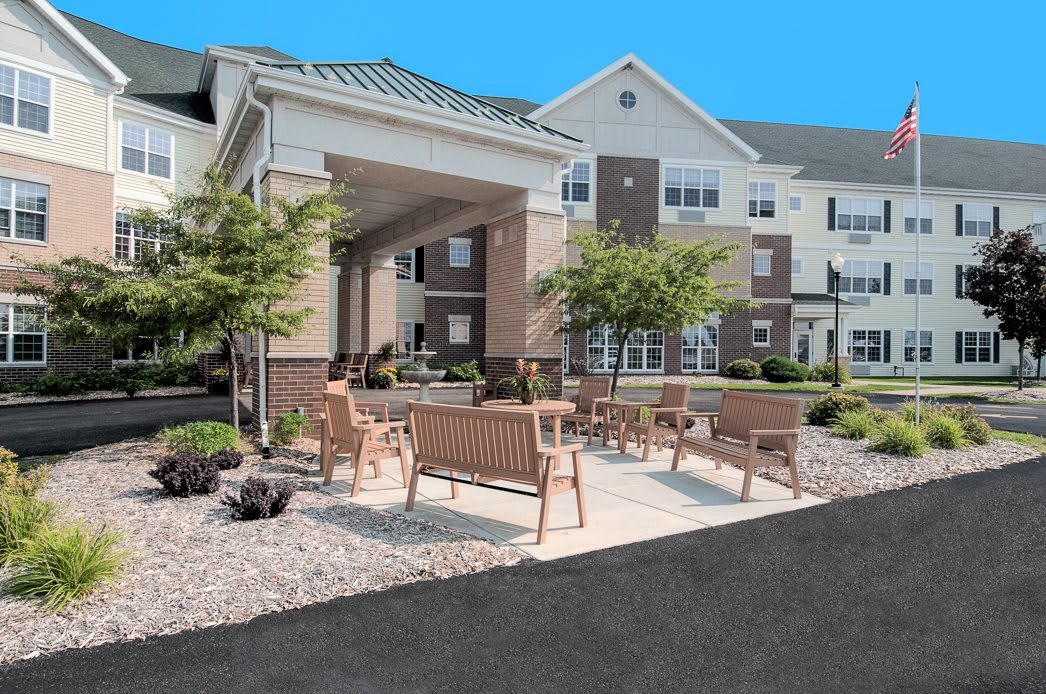 An outdoor seating area with benches in front of a residential building.