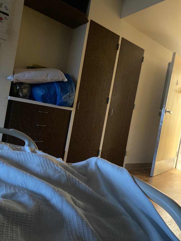 View from a bed in a hospital room showing a wardrobe and an open door.
