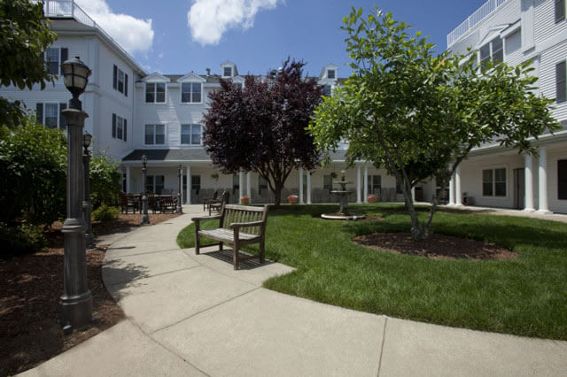 A peaceful courtyard with benches and trees outside a multi-story building.